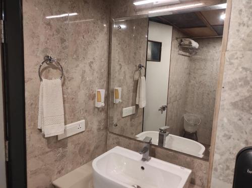 a bathroom with a sink and a mirror at Hotel Vrishali Executive in Kolhapur