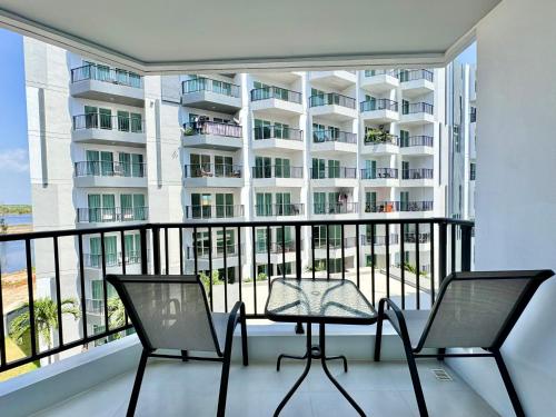 a balcony with two chairs and a table and a building at Mantra Beach Condominium Suite - Mae Phim in Ban Tha Fat