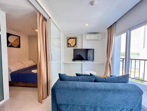 a living room with a blue couch and a bed at Mantra Beach Condominium Suite - Mae Phim in Ban Tha Fat
