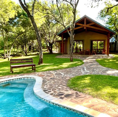 Simunye的住宿－Mbuluzi Game Reserve，一个带长凳和游泳池的房子
