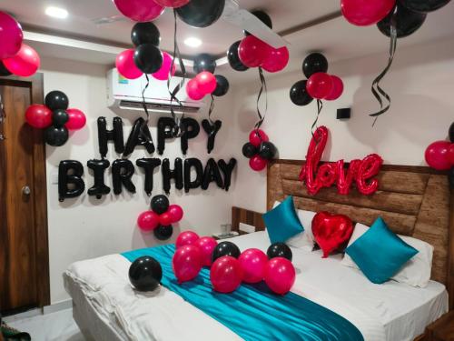 - une chambre avec un lit avec des ballons et un signe d'anniversaire dans l'établissement Hotel Palak Palacce, à Ahmedabad