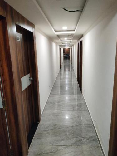 a long hallway with white walls and a long hallway with doors at Hotel Palak Palacce in Ahmedabad