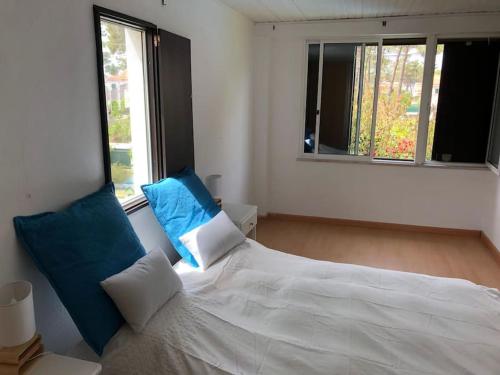 een wit bed met blauwe kussens in een slaapkamer bij La Villa Lisboa: Maison de vacances in Aroeira