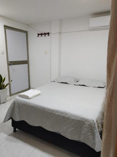 a white bedroom with a large bed with a mirror at Kavala Anisa in Cartagena de Indias