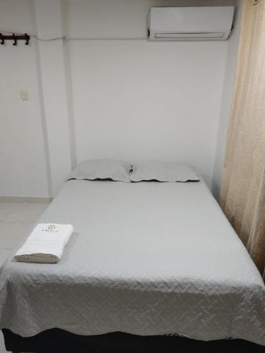 a white bed in a room with a window at Kavala Anisa in Cartagena de Indias