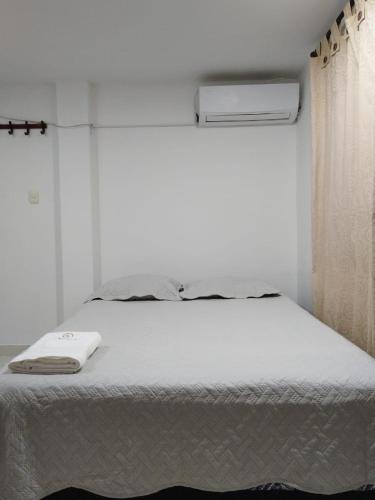 a bedroom with a white bed and a window at Kavala Anisa in Cartagena de Indias