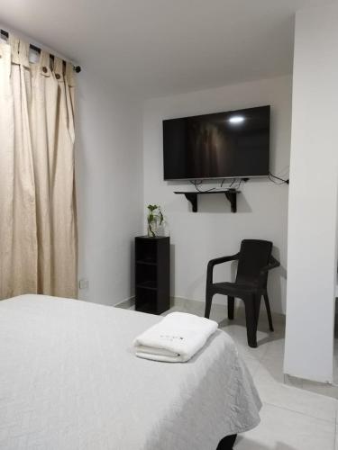 a bedroom with a bed and a chair and a flat screen tv at Kavala Anisa in Cartagena de Indias