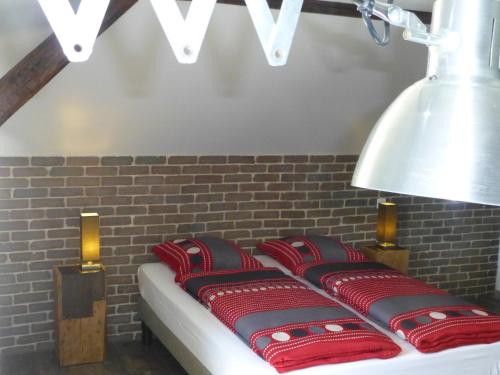 a row of pillows on a bed with a brick wall at L’Été en Novembre in Kirrwiller