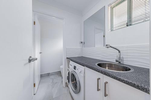 ein Badezimmer mit einem Waschbecken und einer Waschmaschine in der Unterkunft Sunset Waters Apartments in Hamilton Island
