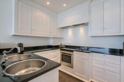 een keuken met witte kasten en een roestvrijstalen wastafel bij 4e verdiep appartement met zeezicht in Knokke in Knokke-Heist
