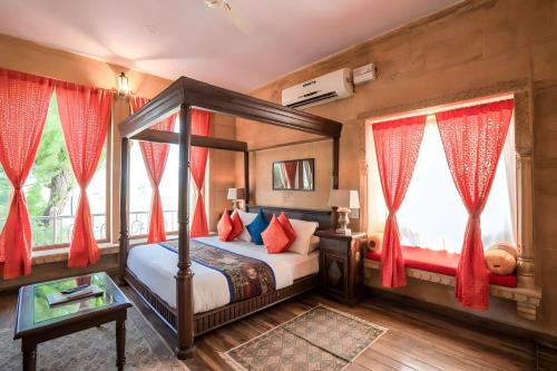 - une chambre avec un lit à baldaquin et des rideaux rouges dans l'établissement Hotel Sun Heaven Senerity, à Jaisalmer