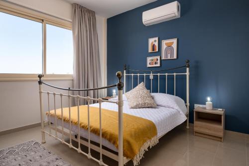 1 dormitorio con 1 cama con pared azul en Zest City Apartment en Pafos