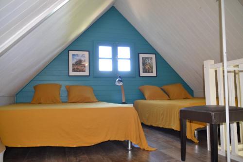 two beds in a attic room with blue walls at La Petite Kaz Dans la Savane in Fleurimont
