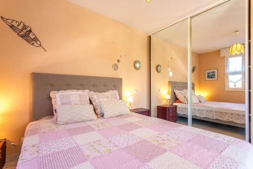 een slaapkamer met een roze bed en een spiegel bij Appartement jardin d'emilie in Saint-Raphaël