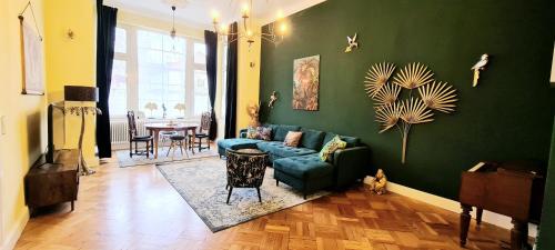 Una sala de estar con un sofá azul y una pared verde. en Stadtvilla Rostock - 160 qm Apartment zentrumsnah, en Rostock