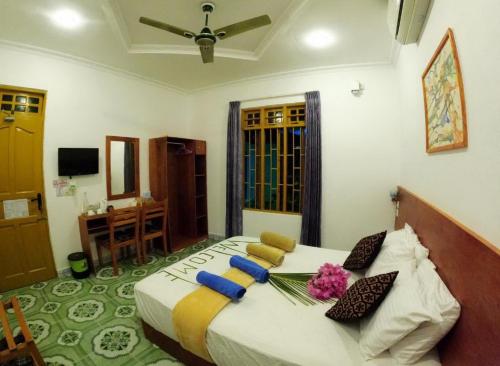 - une chambre avec un grand lit fleuri dans l'établissement Adroit Beach Inn, à Guraidhoo