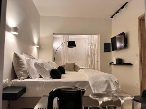 um quarto com uma cama grande com lençóis brancos e almofadas em Perla Coco Jacuzzi Suites em Chania