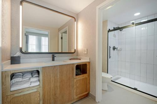 a bathroom with a sink and a mirror and a shower at Hotel Flor Tampa Downtown, Tapestry Collection By Hilton in Tampa