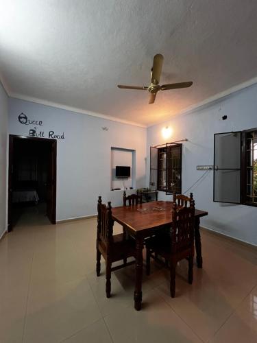 a dining room with a table and chairs and a ceiling fan at MOA Auroville pondicherry in Auroville