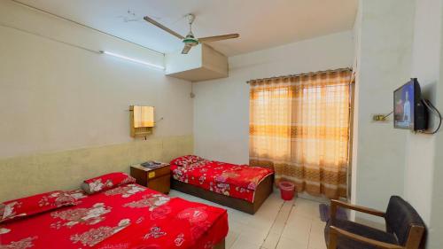 1 dormitorio con 2 camas, TV y ventana en Hotel Al Makka, en Dhaka