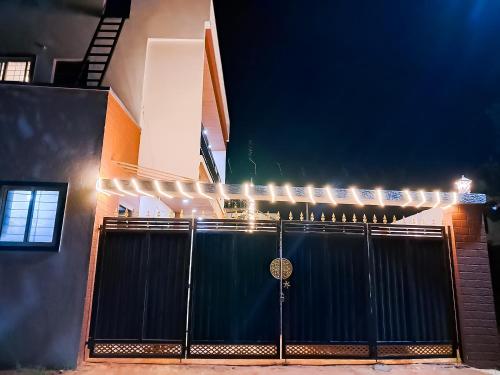 a black gate in front of a building with lights at P Villa in Devanahalli-Bangalore