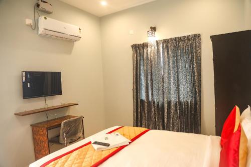 a bedroom with a bed and a tv and a window at FabHotel Home Tree Service Apartment Kolathur in Chennai
