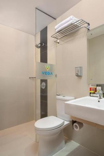 a white bathroom with a toilet and a sink at Vega Hotel Gading Serpong in Serpong