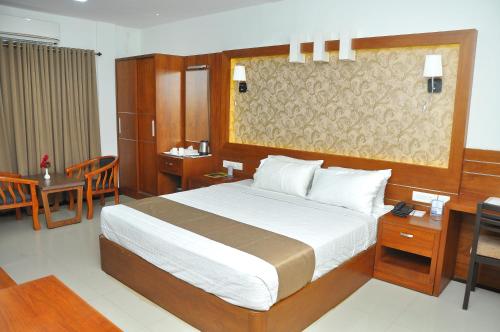 a bedroom with a large bed and a table and chairs at Kallada Mamatha Motels in Kunnamkulam