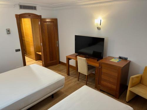 a room with a bed and a desk with a television at Gran Hotel Liber & Spa Playa Golf in Noja
