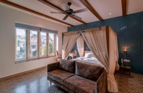 a bedroom with a bed with a ceiling fan and a couch at Jaipur Bungalow in Jaipur