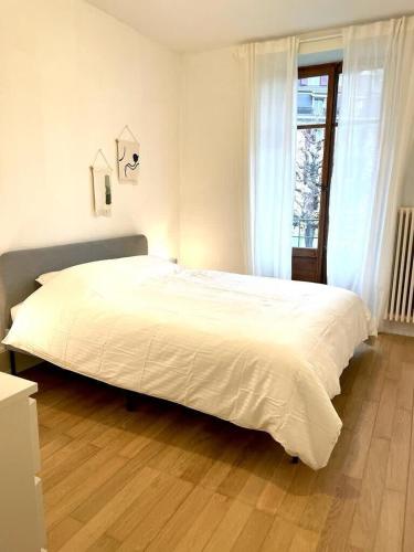 402* City center in Montreux في مونترو: سرير أبيض كبير في غرفة نوم مع أرضية خشبية