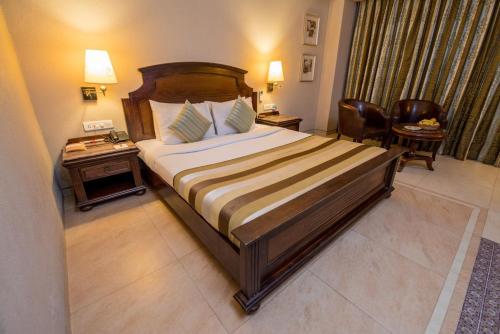 um quarto de hotel com uma cama grande e uma mesa em Hotel Le Cypress em Bareilly