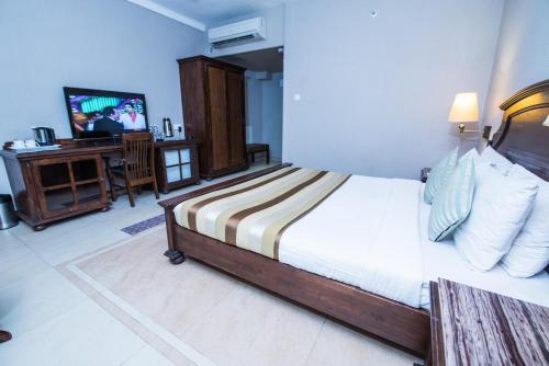 um quarto com uma cama, uma televisão e uma secretária em Hotel Le Cypress em Bareilly