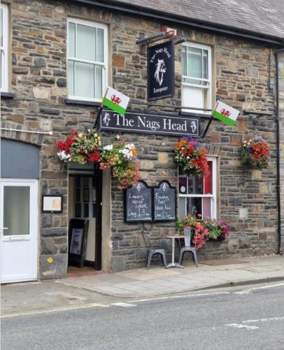 ein Steingebäude mit einem Schild, das den Kopf des Chaos liest in der Unterkunft Nags Head Pub in Lampeter