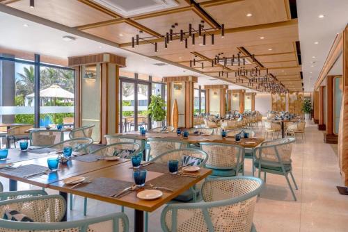 um restaurante com mesas e cadeiras de madeira e janelas em Big Star Villas - Wyndham Garden em Cam Ranh