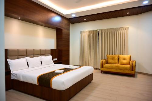 a bedroom with a large bed and a yellow chair at Unnati Stay Inn in Bijāpur