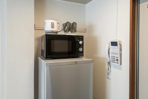 um micro-ondas sentado em cima de um frigorífico em Hale Hotel Miyakojima em Ilhas Miyako