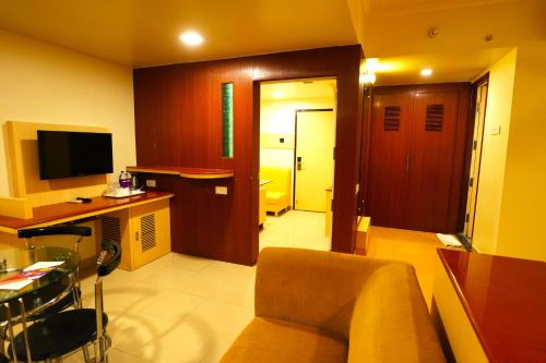 a living room with a couch and a desk and a television at Sai International Hotel in Dāvangere