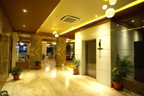 a lobby with potted plants in a building at Sai International Hotel in Dāvangere