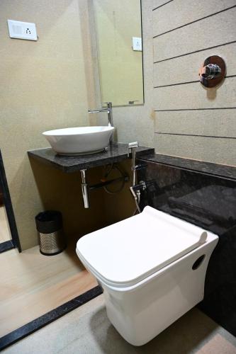 a bathroom with a white toilet and a sink at Unnati Stay Inn in Bijāpur