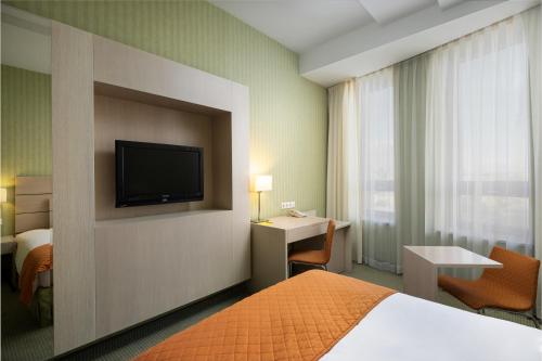a hotel room with a bed and a desk and a television at Hotel Golden Tulip Ana Tower Sibiu in Sibiu