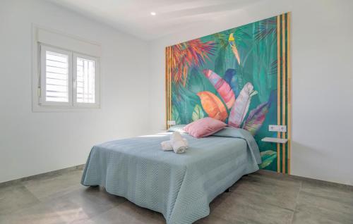 a bedroom with a blue bed with a painting on the wall at 3 Bedroom Awesome Home In Chiclana De La Fronter in Chiclana de la Frontera