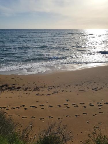 a beach with footprints in the sand and the ocean at Rantos P. Cottage in Dragotiná