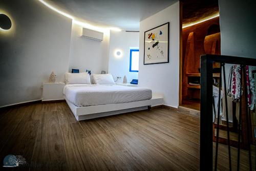 a bedroom with a white bed and wooden floors at Zen Blue Mills in Koundouros