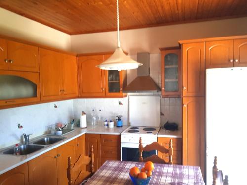 a kitchen with wooden cabinets and a table with oranges on it at Rantos P. Cottage in Dragotiná