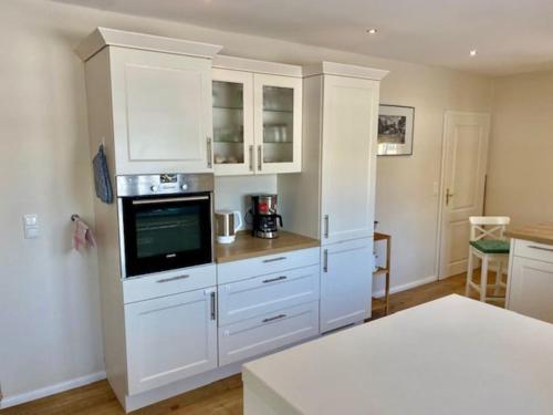 a kitchen with white cabinets and a tv in it at Urlaub mit Hund im Ferienhaus am Wingster Wald in Wingst