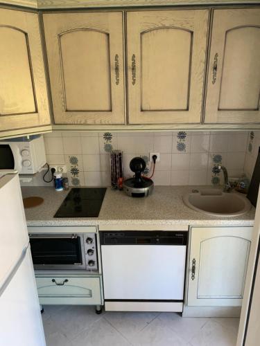 une cuisine avec des armoires blanches et un évier dans l'établissement Appartement RDC très grande terrasse proche mer et centre ville, à Cavalaire-sur-Mer