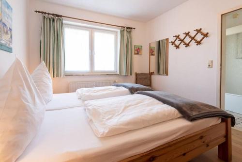 a large white bed in a room with a window at Sonnige Ferien im Nordseegruß 2 in Wenningstedt