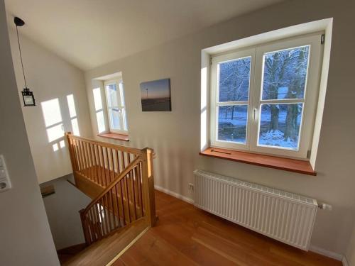an empty room with a staircase and two windows at Urlaub mit Hund im Ferienhaus am Wingster Wald in Wingst