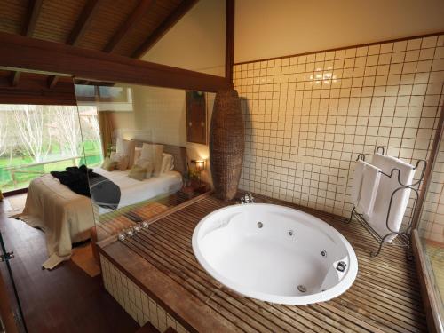 ein Bad mit einer Badewanne und ein Schlafzimmer in der Unterkunft La Corte de Lugás in Lugás